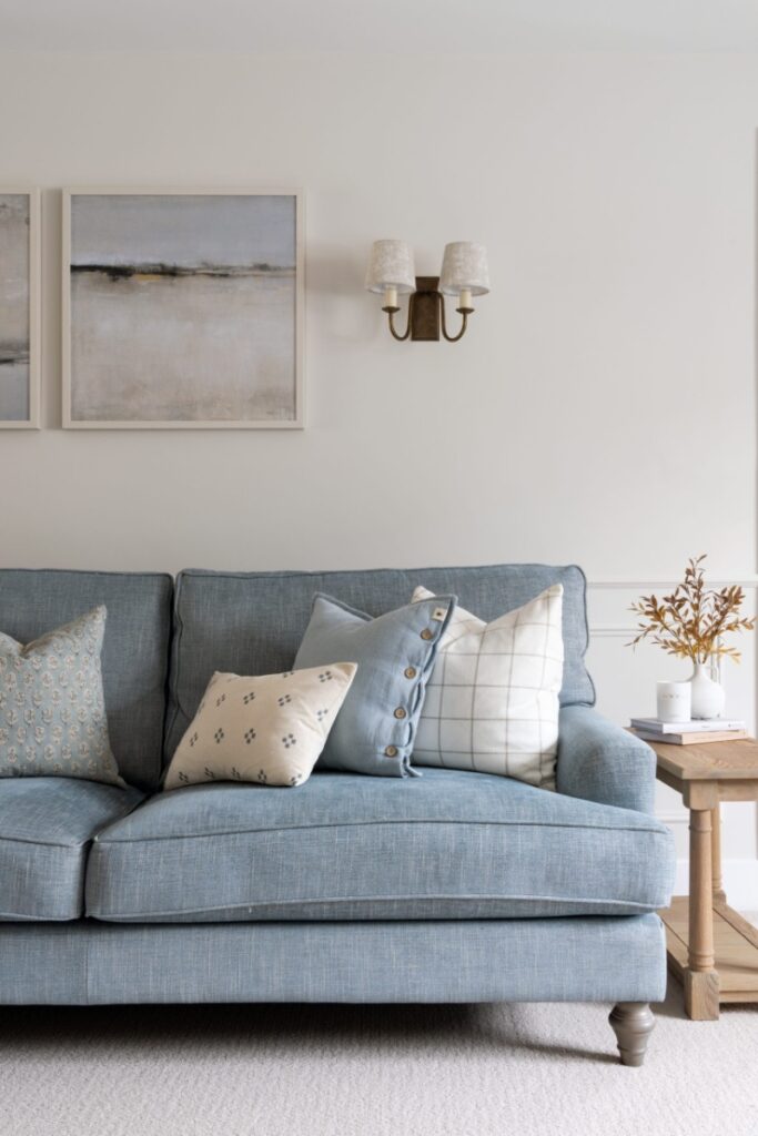 Blue sofa with tone matched cushions beside light wooden sideboard