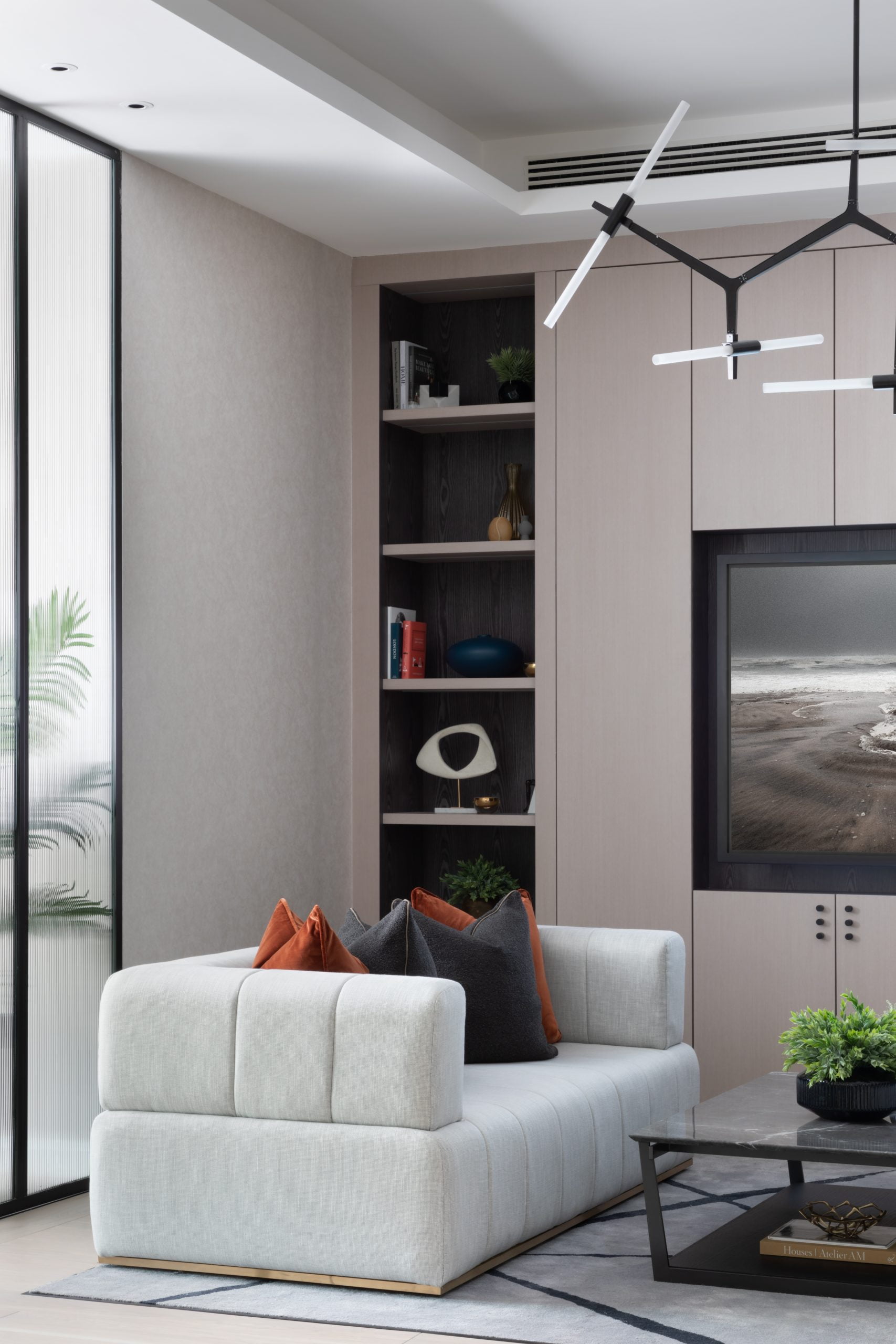 Modern living room design with contemporary light fitting and light coloured sofa by large mounted TV for residential property developers