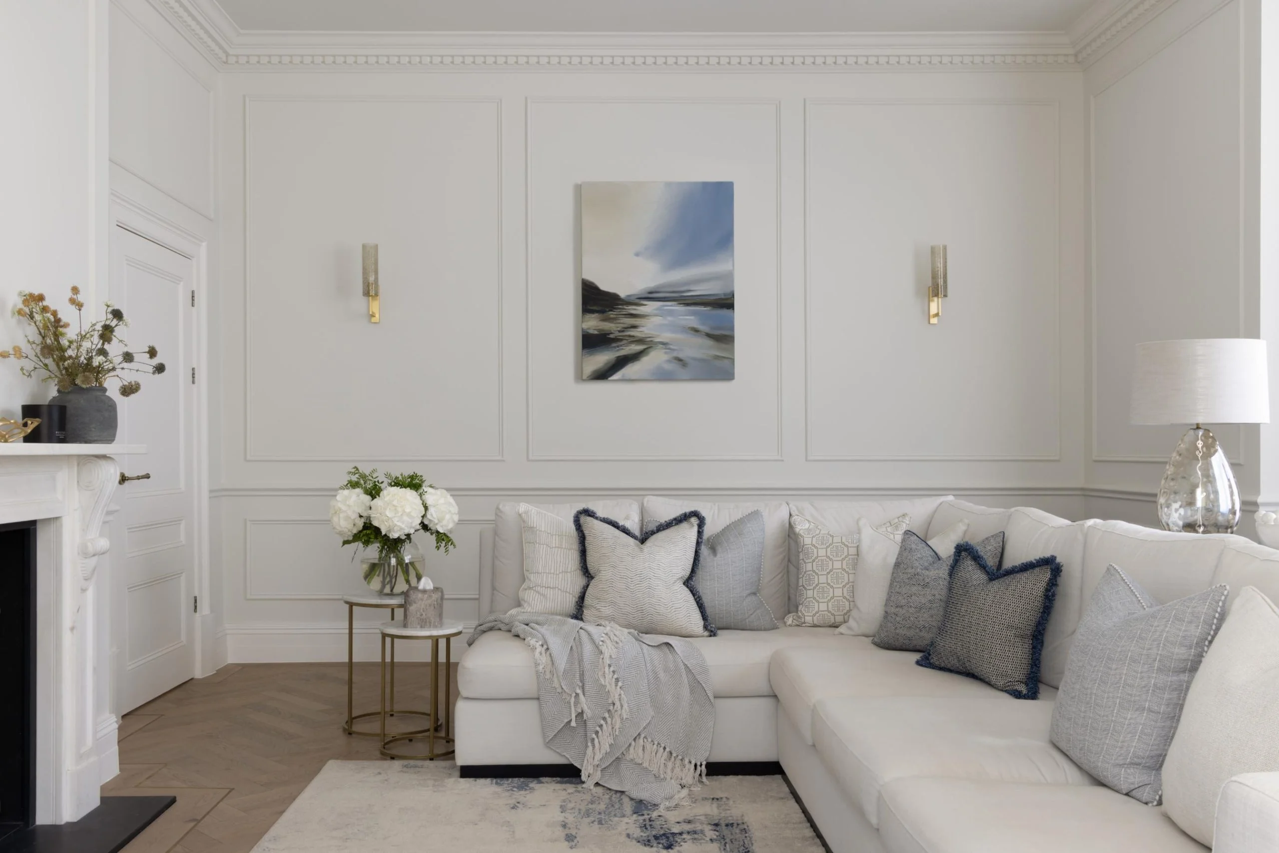 Cream suite with square cushions and small side table with flowers on.