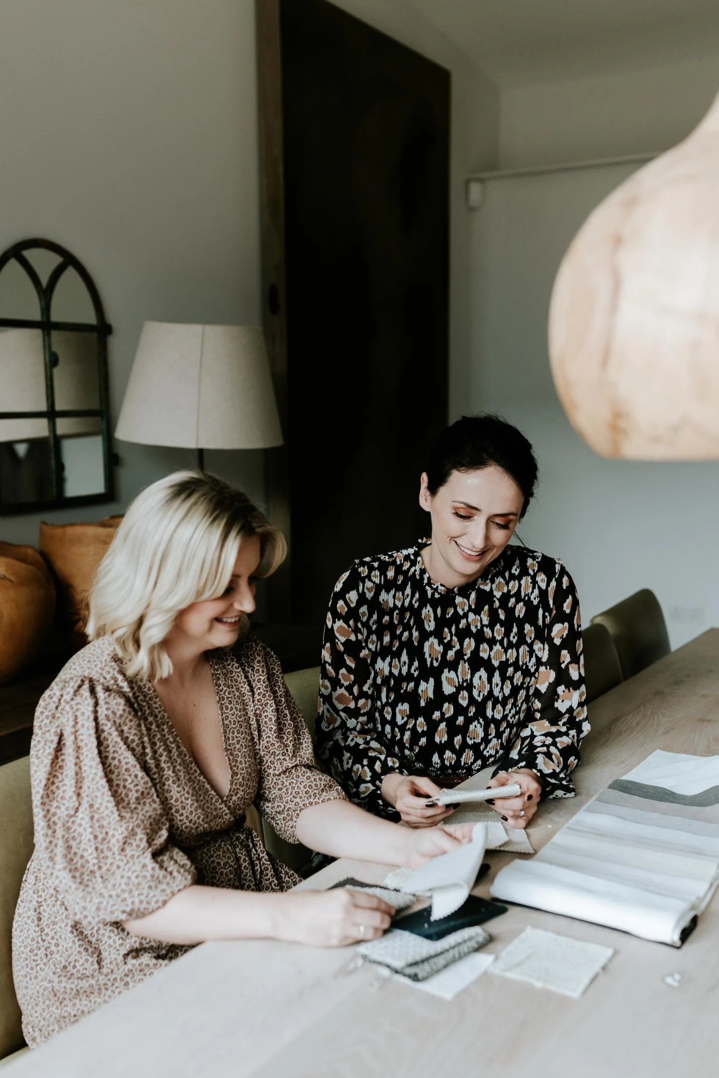 Wells and Maguire Team sitting side by on a table with fabric swatches to hand