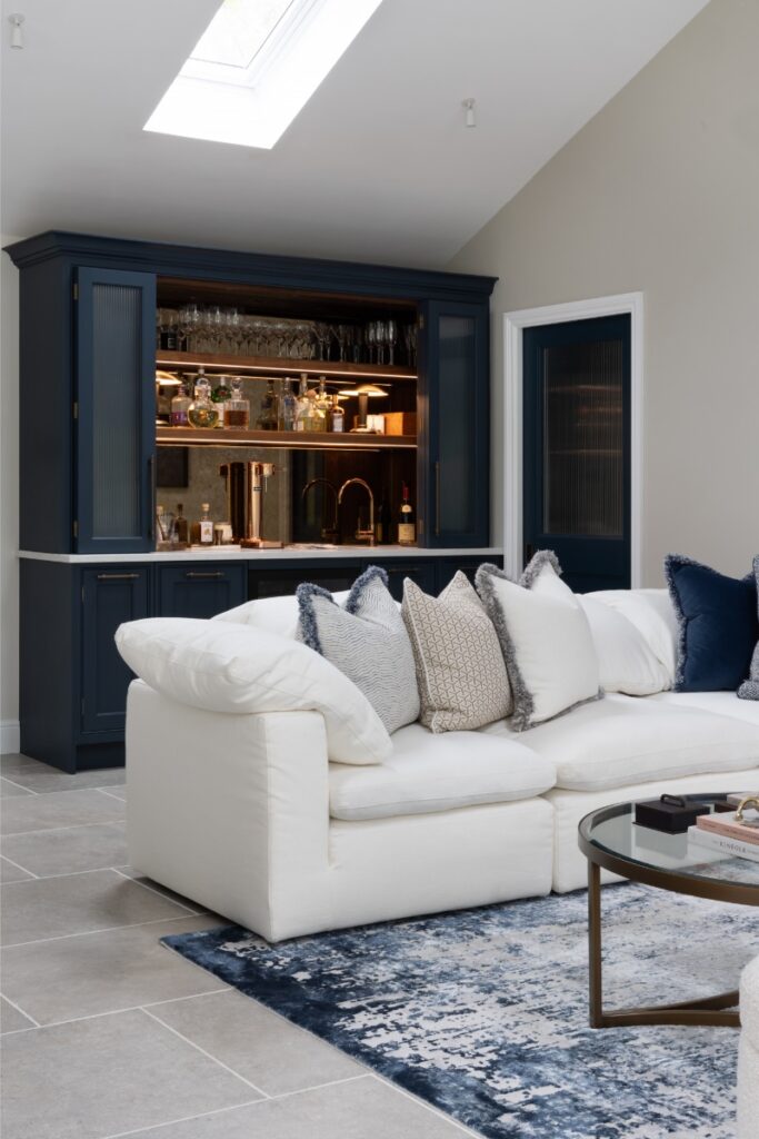 Modern living room with plush white sofa and lit bar unit to reverse